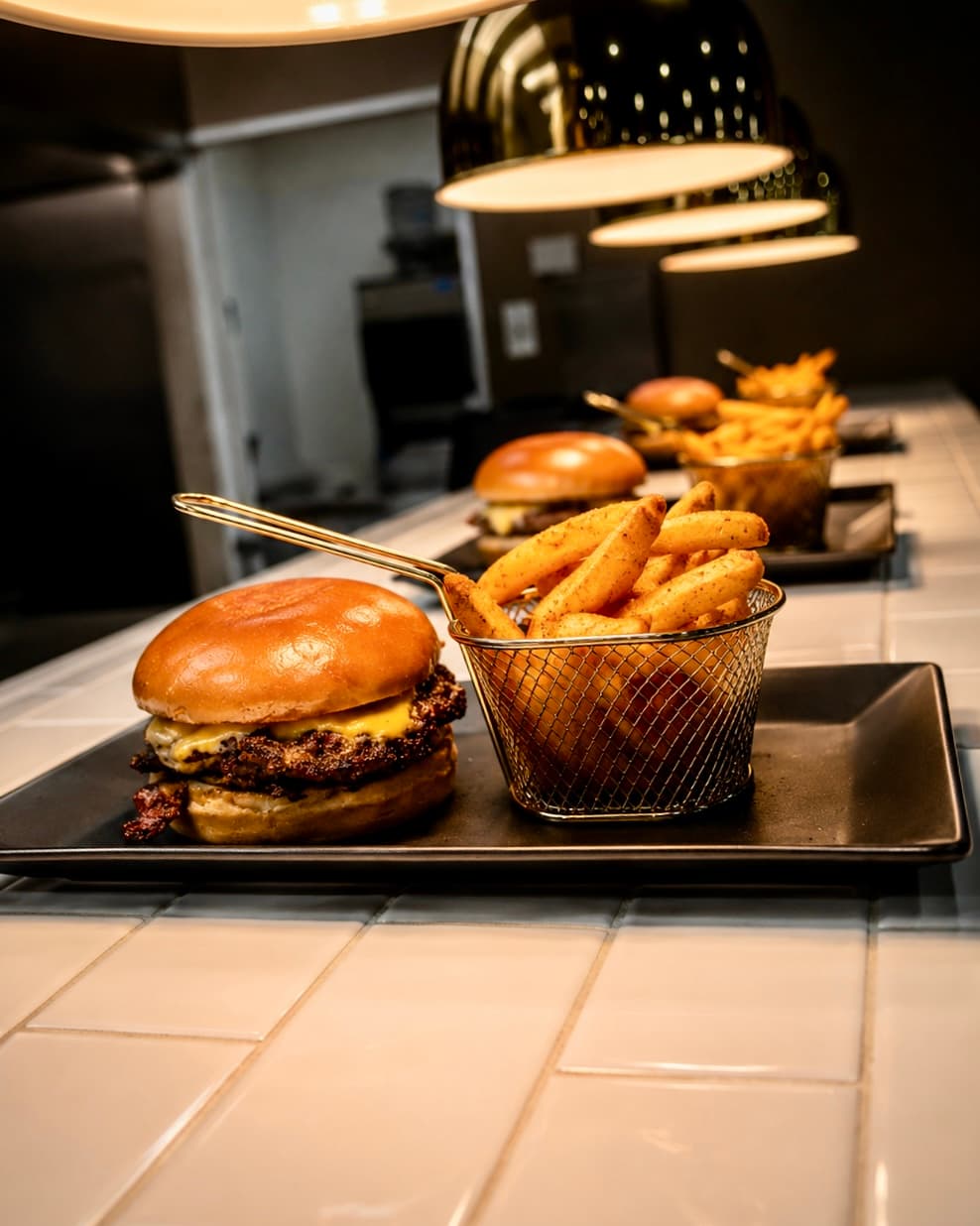 Smash burgers and seasoned fries under heat lamps