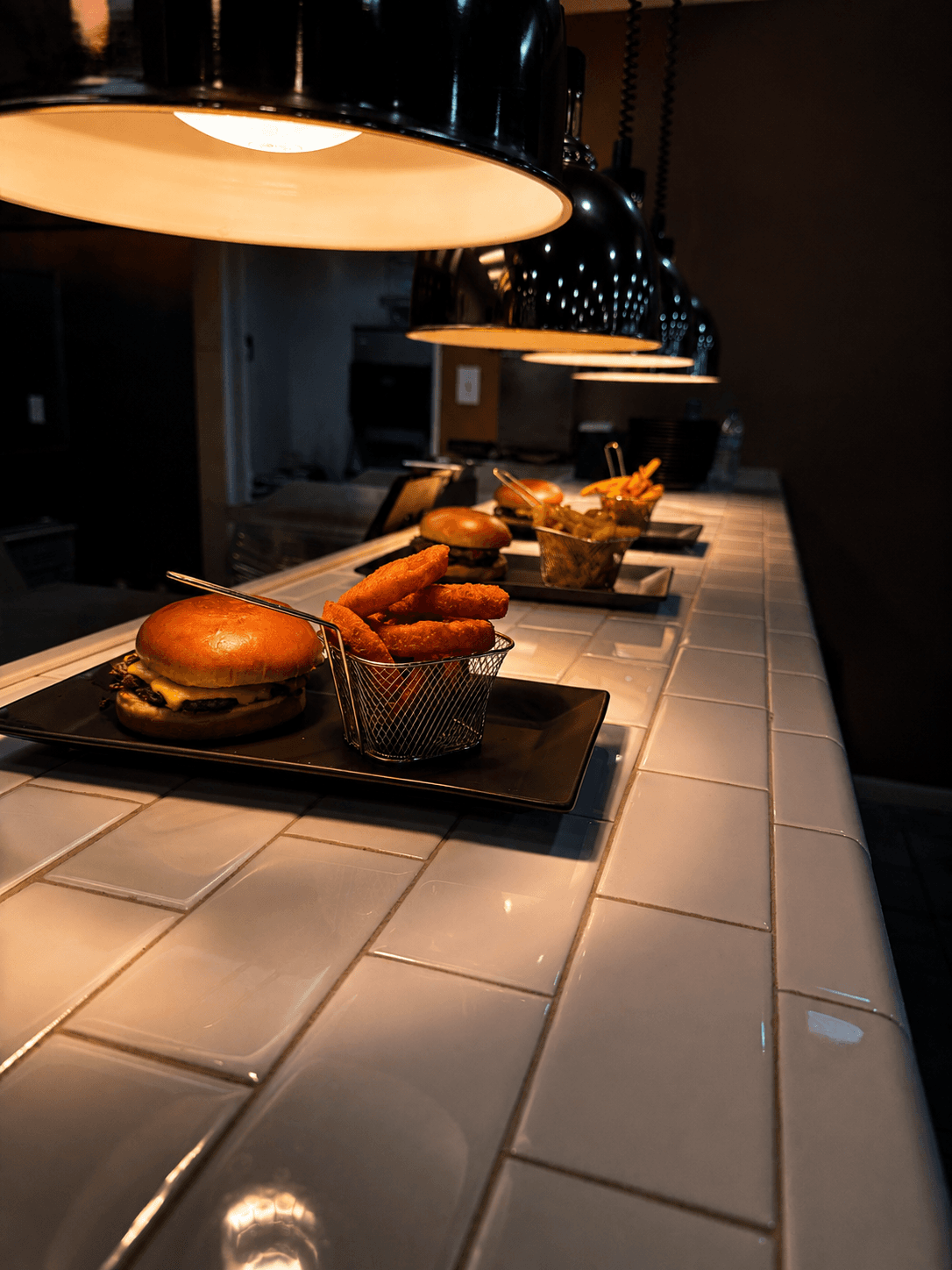 Smash burgers and onion rings under heat lamps