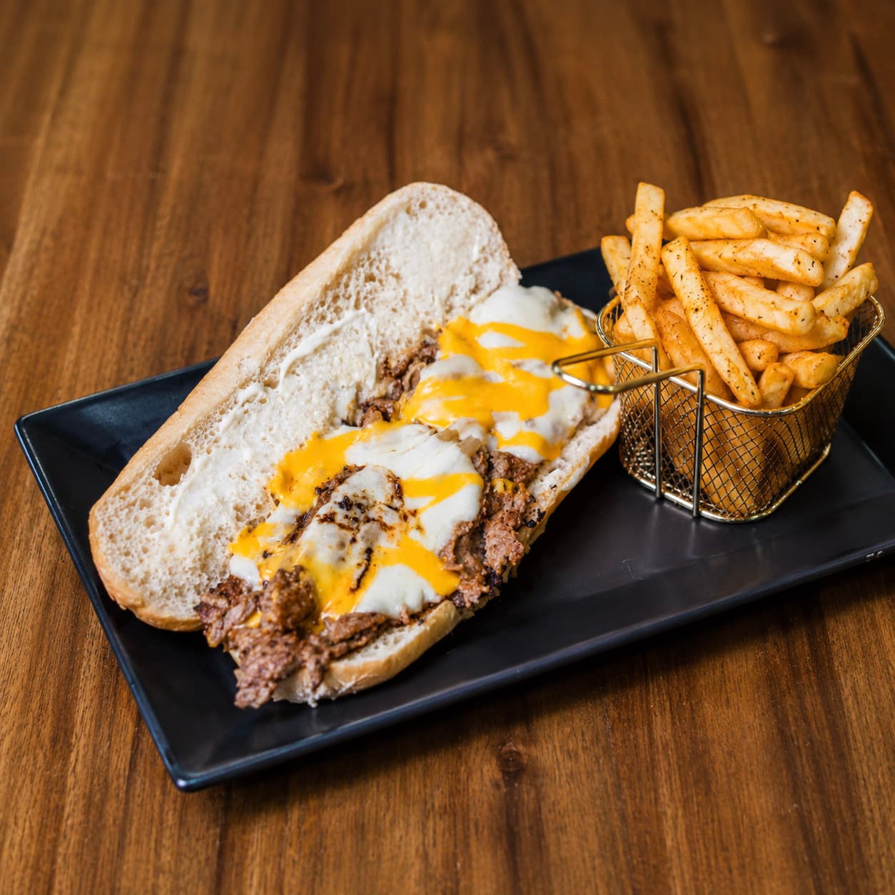 Philly cheesesteak with grilled onions, melted cheese, and french fries