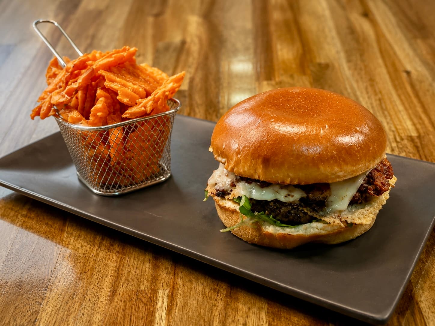 Rise and Smash burger with sweet potato waffle fries on a slate plate