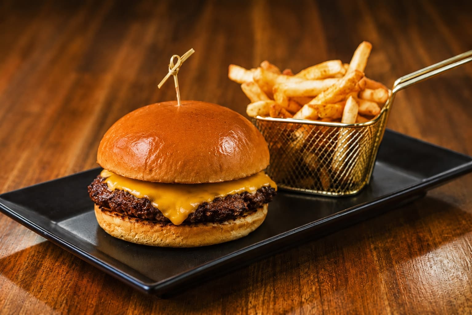 Single Smash cheeseburger with seasoned fries on a black plate
